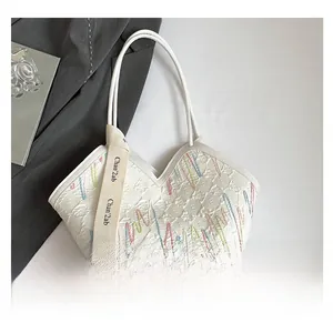 Detail of white tote bag featuring colorful wavy embroidery and stylish wide fabric strap
