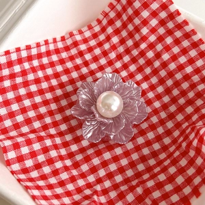 Detail of lavender metal flower phone socket with a glossy pearl center on checkered fabric