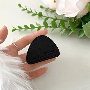 Detail of black triangle leather phone grip with mountain engraving and fine stitching