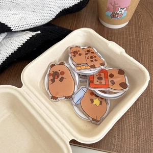 Close-up of cute acrylic capybara phone sockets in various poses on a cozy background