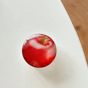 Close-up of 3D resin red apple phone grip with a glossy finish on white surface