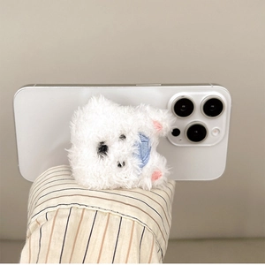 Close-up of white plush puppy phone grip with blue scarf on a smartphone back