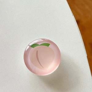 Close-up of a cute 3D resin peach phone grip with a glossy finish on a white surface