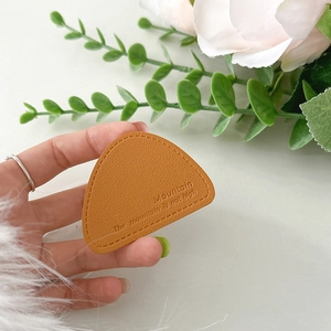 Detailed close-up of brown pebbled leather triangular phone grip with embossed quote