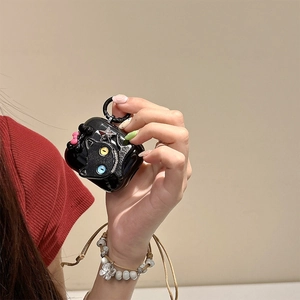 Dettaglio custodia AirPods nera glitterata con gatto 3D e stelle tenuta da un modello