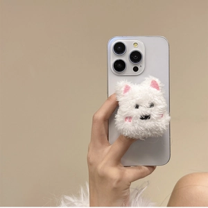 Close-up of white plush puppy phone socket holder on smartphone held by a hand
