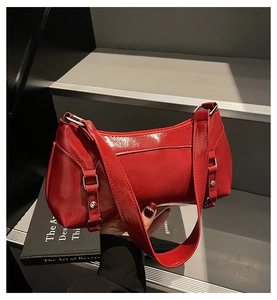 Close-up of red patent leather shoulder bag featuring criss-cross lace-up details