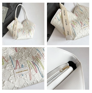 Detail of striped canvas tote showing embroidery texture, wide strap and inner zipper