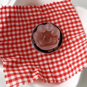 Close-up of pink cat paw phone grip with heart detail on red checkered background