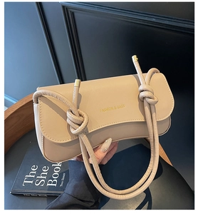 Detail of beige shoulder bag with knotted strap and gold foil fashion logo print