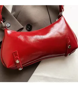 Detail view of red patent leather underarm bag featuring silver rivets and glossy finish
