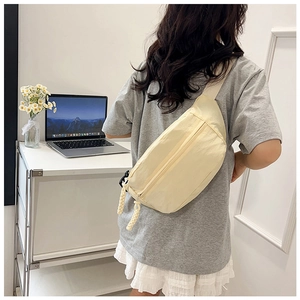 Detail of cream canvas chest bag with woven rope zipper and adjustable wide shoulder strap