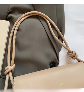 Detailed close-up of apricot baguette bag with decorative knot and long shoulder strap