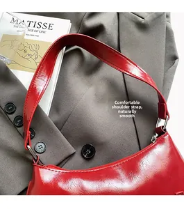 Detail of the smooth red patent leather shoulder strap with polished silver metal hardware