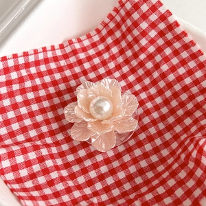 Close-up of pearl flower phone grip with pink translucent petals on checkered background