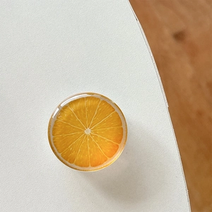 Close-up of a glossy orange slice phone grip with realistic resin texture on a desk