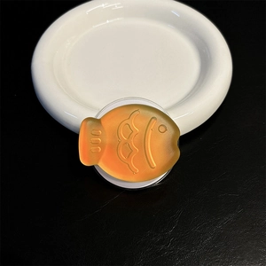 Close-up of orange fish-shaped magnetic phone grip with semi-transparent resin finish