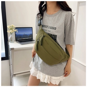 Detail of army green nylon chest bag featuring durable zippers and woven pullers