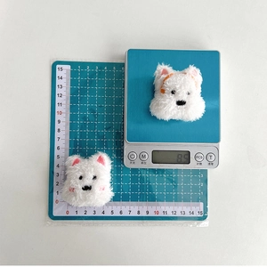 Macro shot showing white plush puppy phone grip dimensions on a measuring mat