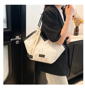 Detail of white quilted tote bag with colorful embroidery and wide canvas shoulder strap