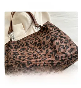 Detail shot of leopard print canvas tote bag with brown leather strap and silver ring