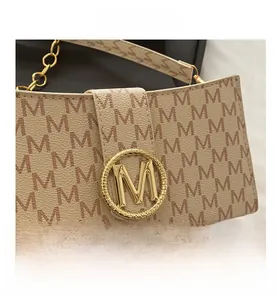 Detailed close-up of beige crossbody bag with M-logo pattern and golden M-buckle