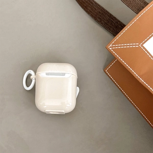 Dettaglio custodia in silicone crema per AirPods con gancio bianco su grigio