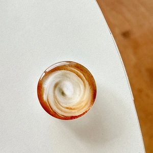 Close-up of a round latte art phone grip with glossy epoxy finish on a white surface