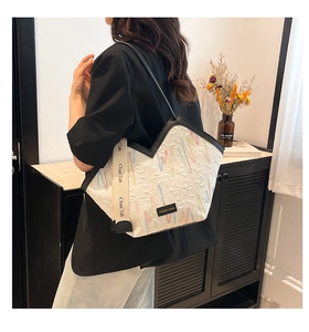 Detail of white quilted tote bag with colorful embroidery and a wide woven shoulder strap
