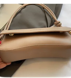 Detail view of khaki leather shoulder bag with gold clasp and knotted strap design