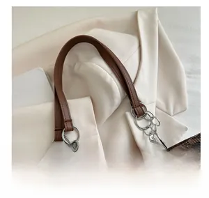 Detail of leopard print fabric bag with brown leather handle and silver metal rings
