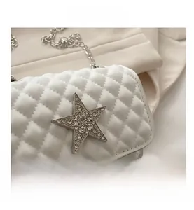 Close-up of white quilted mini bag with rhinestone star charm and silver chain strap