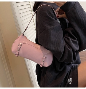 Close-up of pink glossy underarm bag with silver buckles shown on a female model