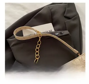 Detail of trendy crossbody bag showing 'M' print pattern and gold chain strap link