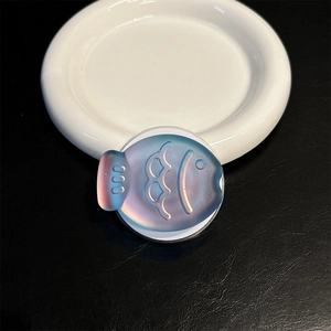 Macro shot of fish-shaped laser phone grip with holographic gradient on black leather