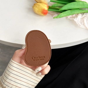 Close-up of brown leather mango-shaped phone grip with litchi texture and gold stamping