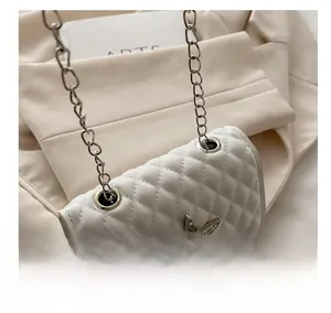 Close-up of white quilted crossbody bag featuring star-shaped rhinestone buckle and chain
