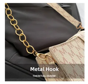 Macro detail of golden metal hook with red M letter pattern on beige lychee leather