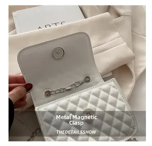 Macro view of white quilted crossbody bag with silver magnetic snap button closure