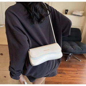 Detail of minimalist cream leather shoulder bag with wavy flap and golden text