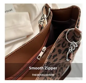 Detail of a smooth silver zipper closure on a leopard print tote bag with brown leather trim