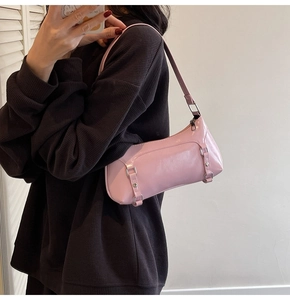 Detail view of pink minimalist baguette bag with decorative buckles on dark waffle shirt