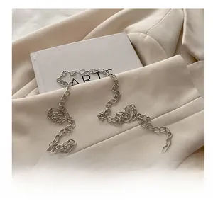Detail of silver chain strap and star emblem on white quilted crossbody bag