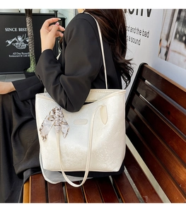 Close-up of white snake-textured tote bag featuring an elegant printed handle scarf