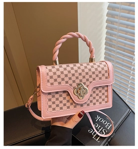Detail view of pink plaid handbag with twisted handle and golden petal-shaped buckle