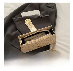 Close-up of beige printed shoulder bag showing spacious interior and secure metal lock