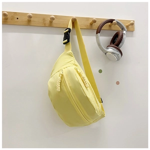 Detail of a yellow crescent canvas chest bag hanging on a wooden hook with smooth zippers