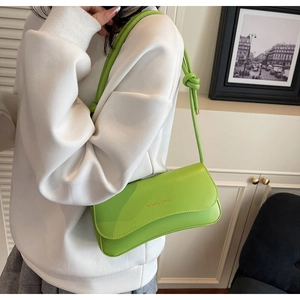 Close-up of vibrant lime green rectangular leather bag with knotted rope shoulder strap