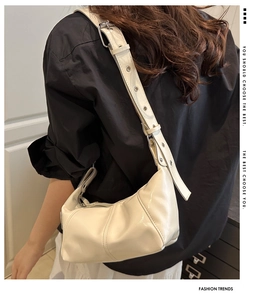 Detailed view of the creamy white croissant bag featuring pleated texture and silver buckle