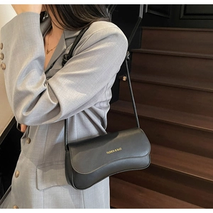 Detail of minimalist black matte leather shoulder bag with gold FASHION & BAGS lettering